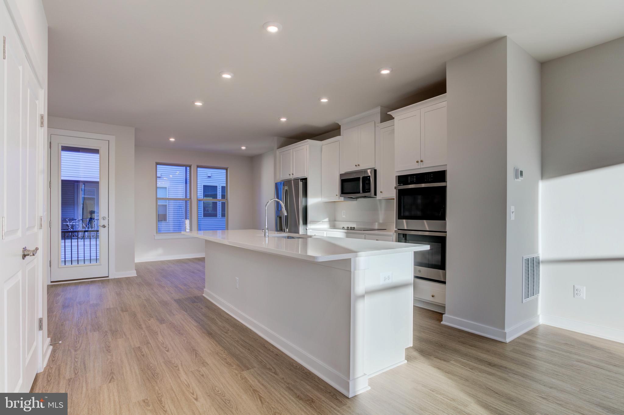 13172 Arches Road Herndon, VA 20170 - Photo 6 of 31 a kitchen with stainless steel appliances kitchen island wooden floors and white cabinets