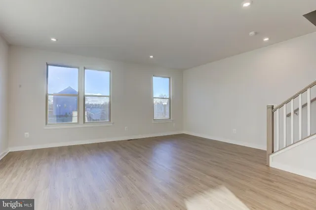 a view of an empty room with wooden floor and window