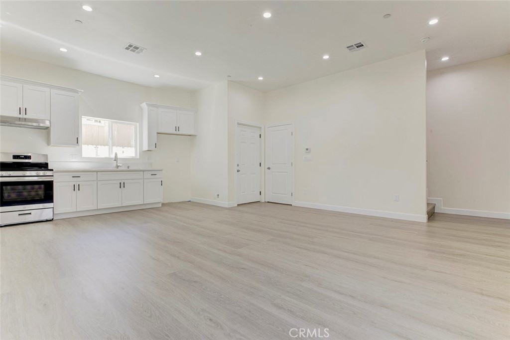 7044-2 Greeley Street Tujunga, CA 91042 - Photo 4 of 20 an empty room with wooden floor and white cabinets