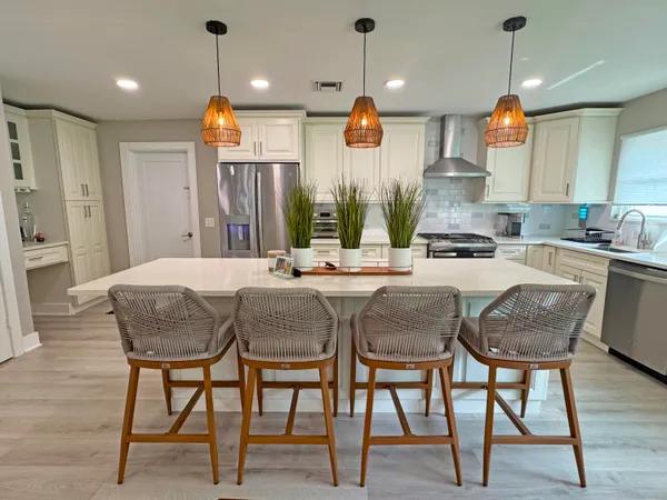 a kitchen with stainless steel appliances granite countertop wooden floor dining table chairs and wooden floor
