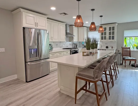 a kitchen with stainless steel appliances a refrigerator a stove a sink a dining table and chairs with wooden floor