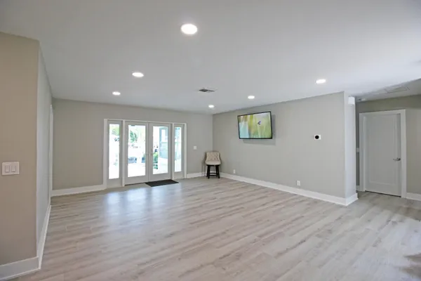 a view of an empty room with wooden floor and a window