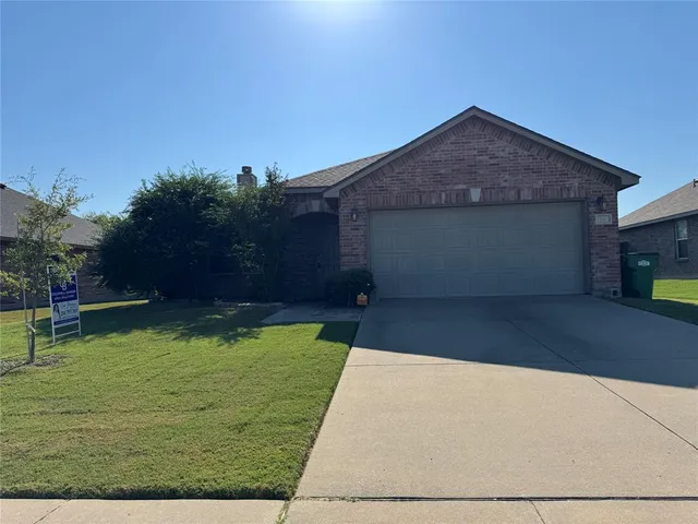 a front view of house with yard and trees in the background