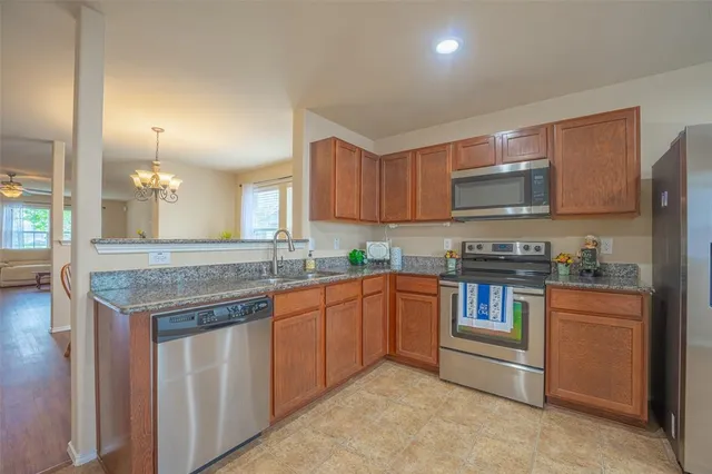 a kitchen with kitchen island granite countertop a stove top oven a sink dishwasher and cabinets with wooden floor