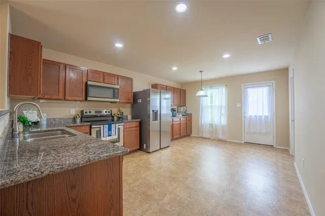 a kitchen with stainless steel appliances granite countertop a stove a sink a refrigerator a microwave and cabinets