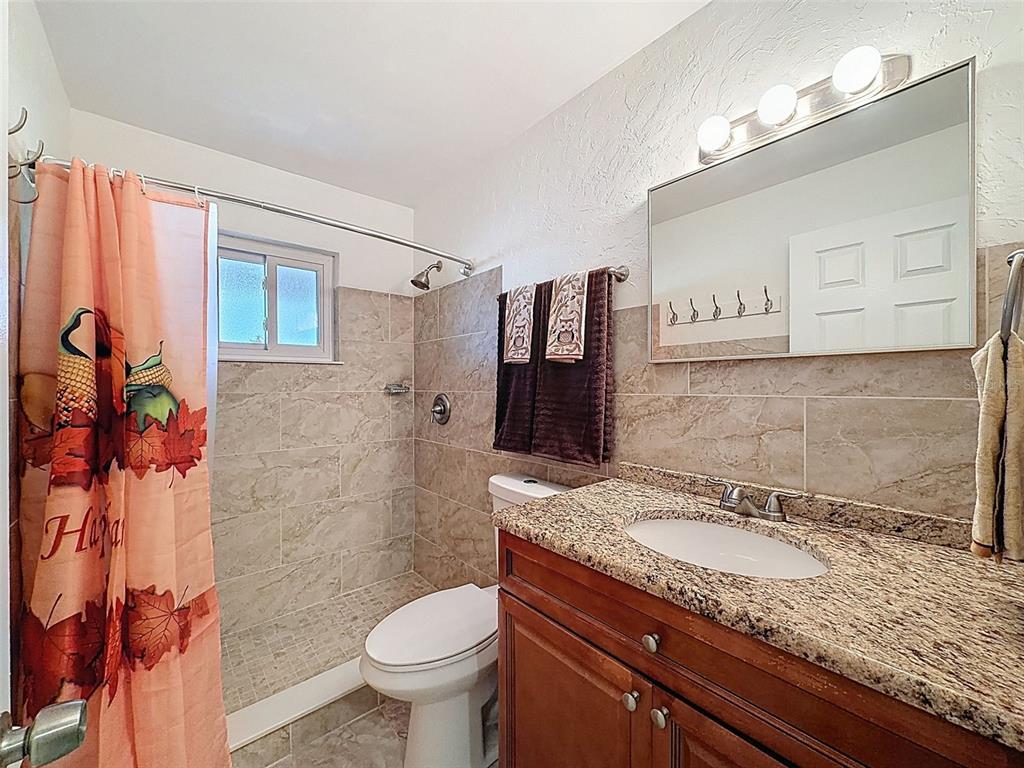 8716 Green Street Port Richey, FL 34668 - Photo 18 of 42 a bathroom with a granite countertop sink toilet and shower