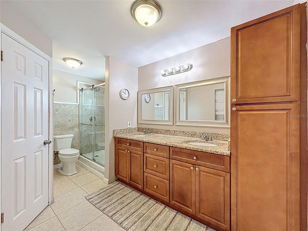 8716 Green Street Port Richey, FL 34668 - Photo 21 of 42 a bathroom with a granite countertop sink a toilet a mirror and shower