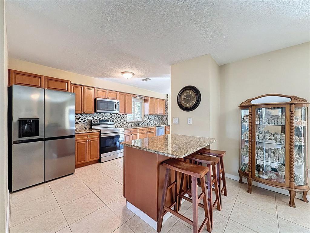 8716 Green Street Port Richey, FL 34668 - Photo 6 of 42 a kitchen with stainless steel appliances granite countertop a refrigerator a stove top oven and a sink with granite countertops