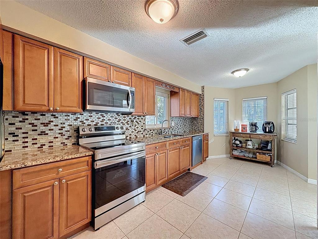8716 Green Street Port Richey, FL 34668 - Photo 7 of 42 a kitchen with granite countertop a sink cabinets and stainless steel appliances
