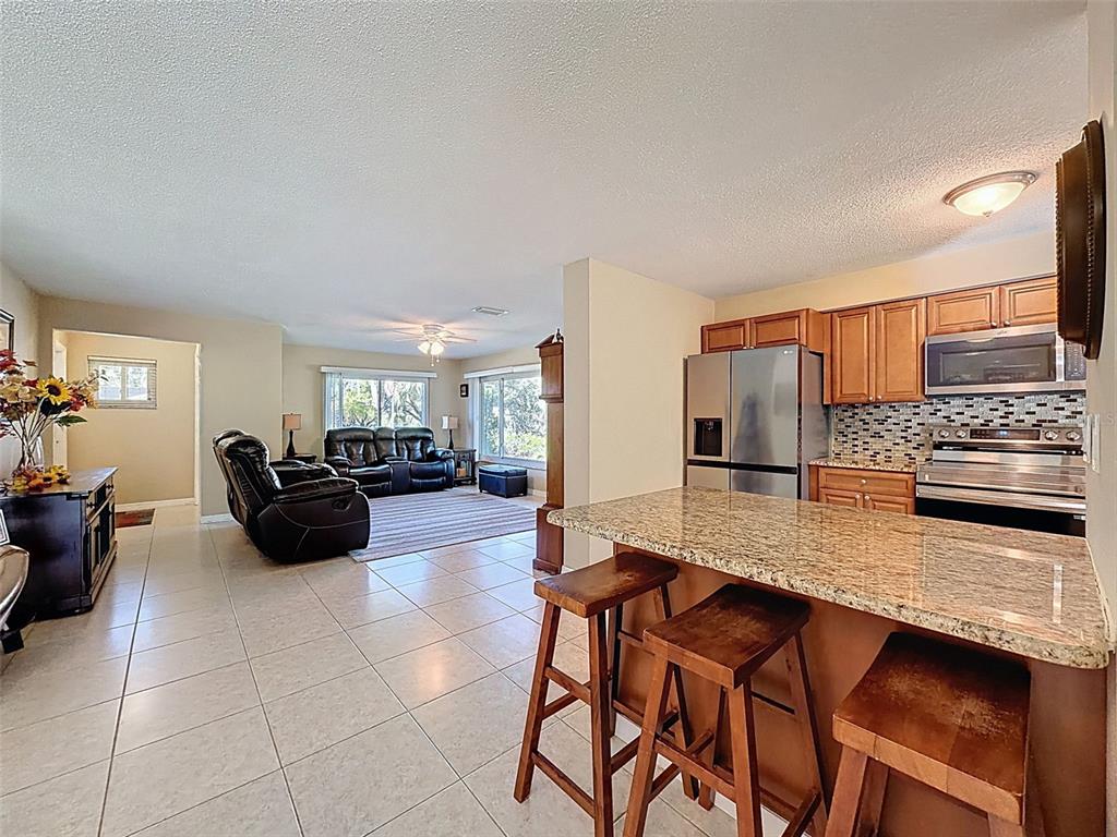 8716 Green Street Port Richey, FL 34668 - Photo 9 of 42 a kitchen with stainless steel appliances kitchen island granite countertop a table and chairs in it