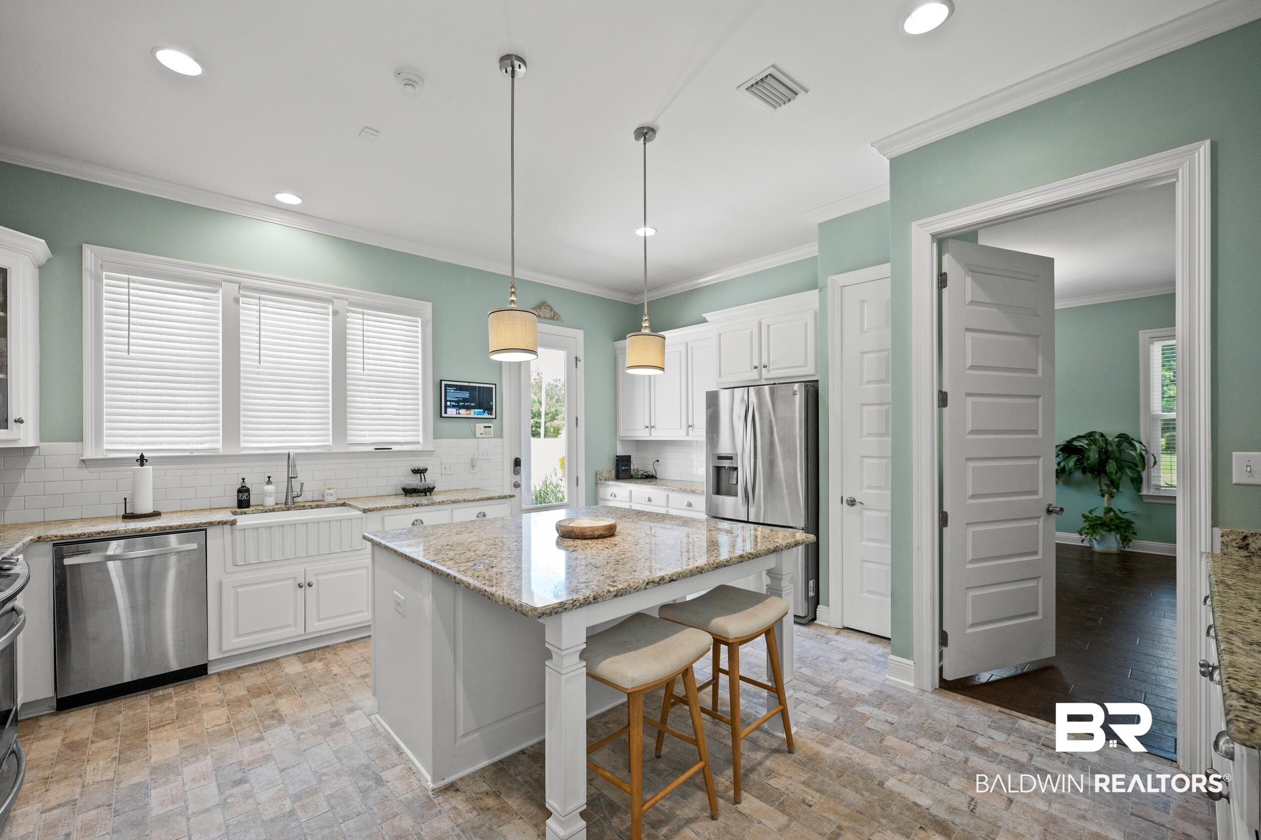 9060 Bromley Road Bay Minette, AL 36507 - Photo 19 of 63 Kitchen featuring appliances with stainless steel finishes, backsplash, a kitchen island, white cabinetry, and ornamental molding