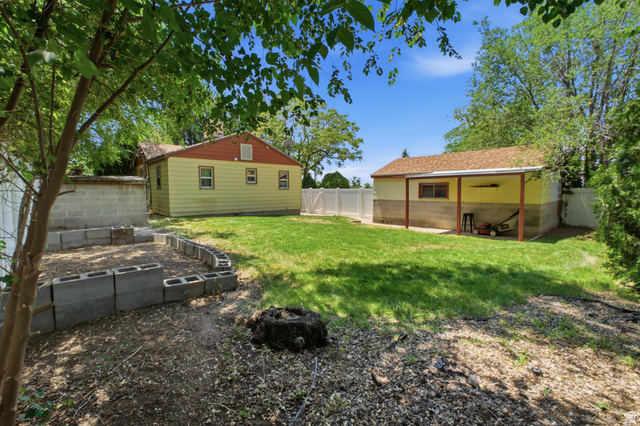 94 West 2000th Street North Clearfield, UT 84015 - Photo 23 of 26 Backyard view showing the detached garage, fenced yard, and additional garden or landscaping space.