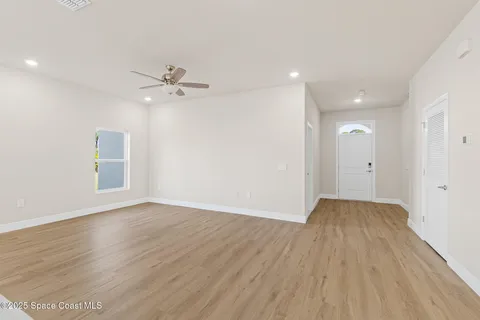 a view of an empty room with a window and wooden floor