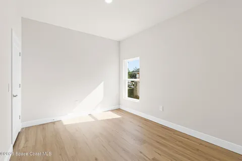 a view of a room that has wooden floor and a window