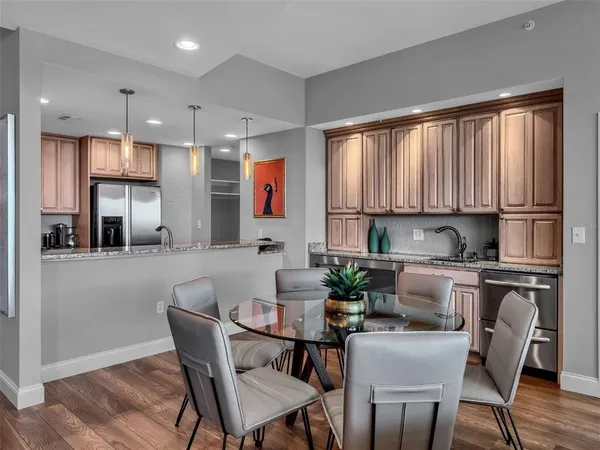 a kitchen with stainless steel appliances granite countertop a stove top oven a sink dishwasher a dining table and chairs with wooden floor