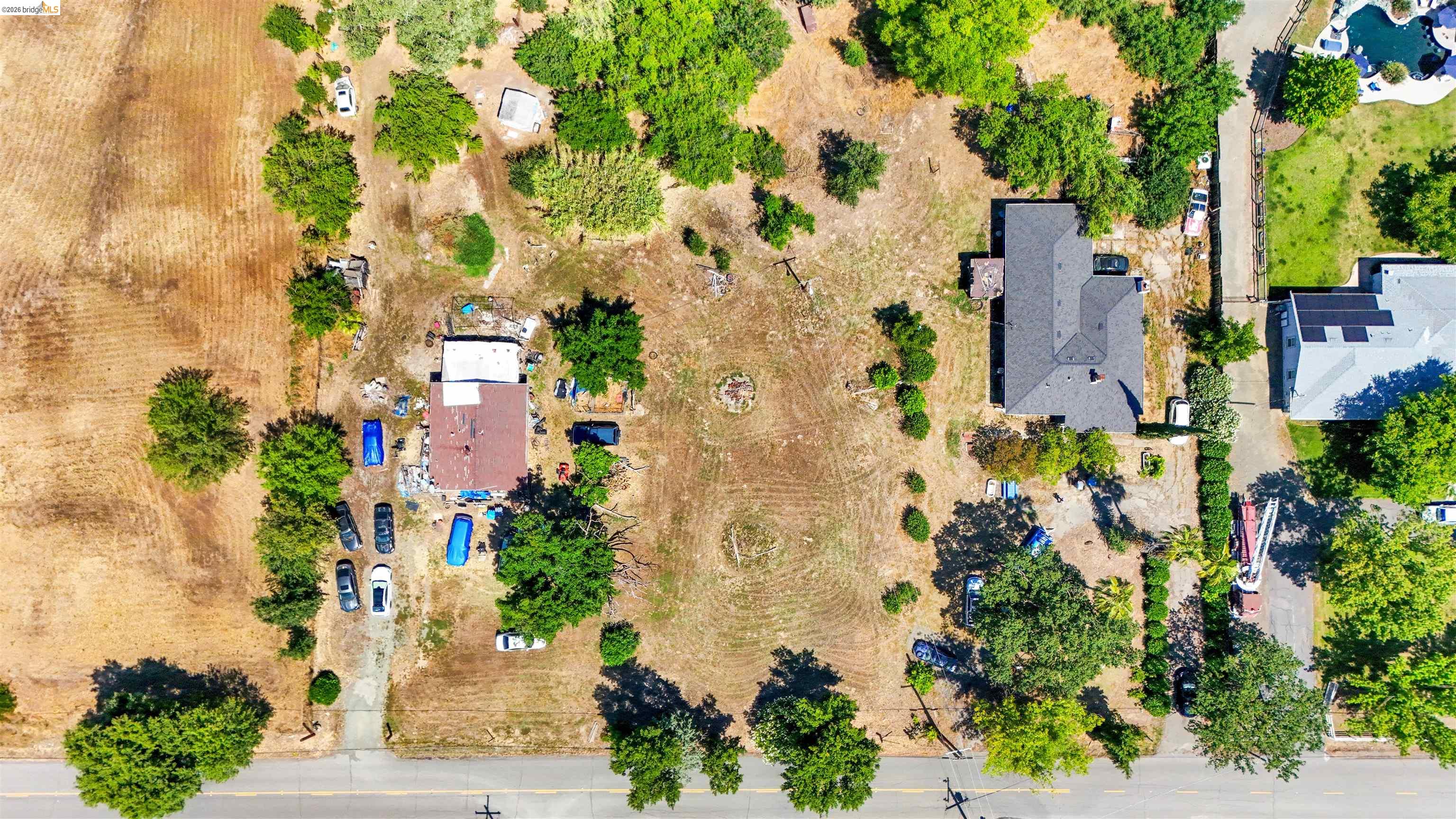 7750 Locke Road Vacaville, CA 95688 - Photo 7 of 23 Expansive property featuring two distinct structures, mature trees, and a paved driveway entrance from the street