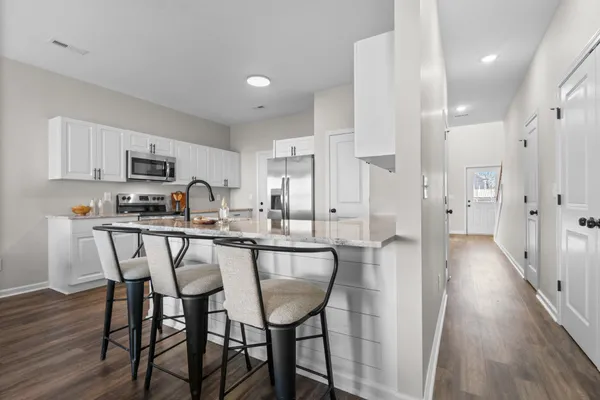 a kitchen with stainless steel appliances a dining table chairs and a refrigerator