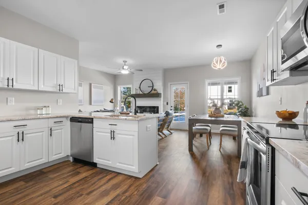 a kitchen with white cabinets a sink dining table and chairs