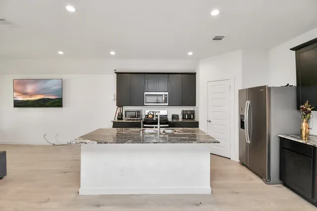 a kitchen with kitchen island stainless steel appliances a sink a stove a microwave a counter top and cabinets