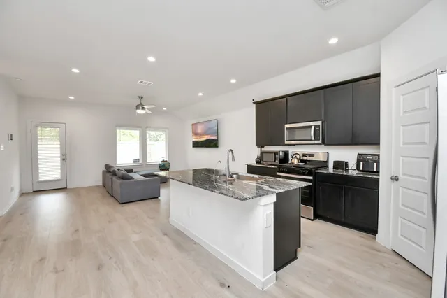 a large kitchen with stainless steel appliances lots of counter space and a sink