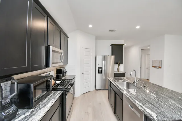 a kitchen with stainless steel appliances granite countertop a stove a sink and a refrigerator