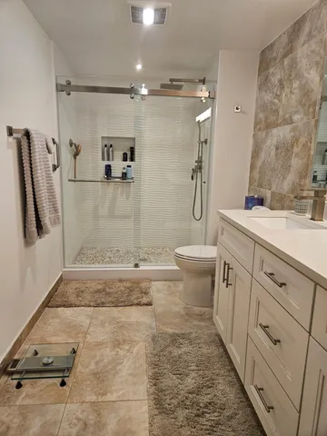 a bathroom with a granite countertop sink toilet and shower