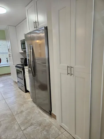 a view of a refrigerator in kitchen and an empty room