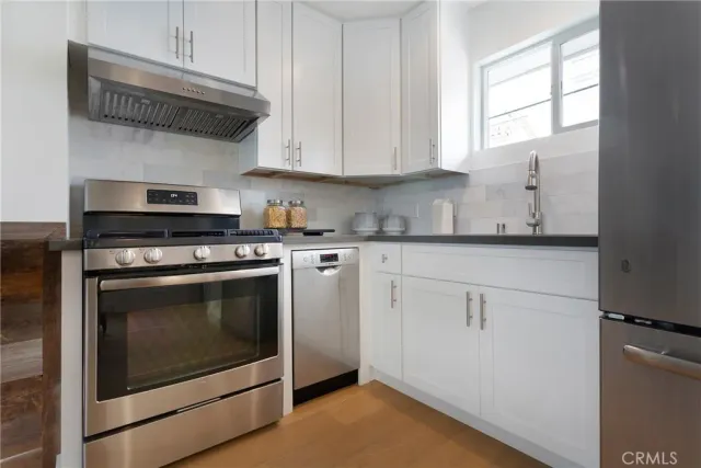 a kitchen with stainless steel appliances white cabinets and a stove top oven