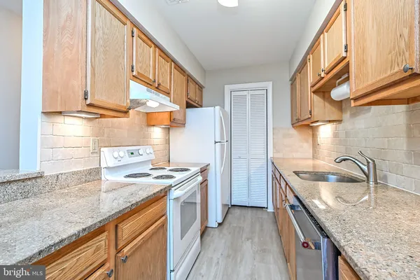 a kitchen with stainless steel appliances granite countertop a sink a stove and a wooden floors