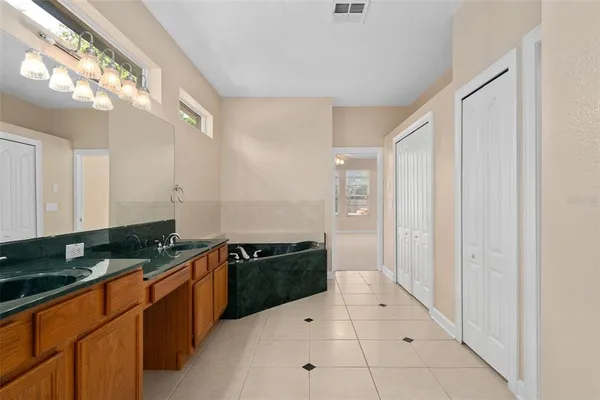an empty room with chandelier fan and windows