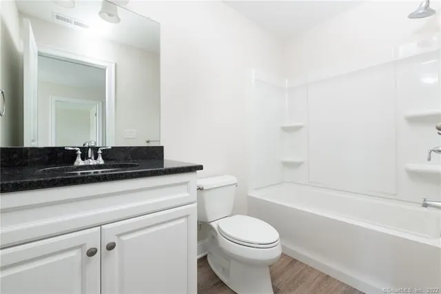 a bathroom with a granite countertop sink a toilet and bathtub
