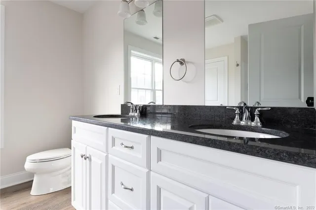 a bathroom with a granite countertop sink a toilet and a mirror
