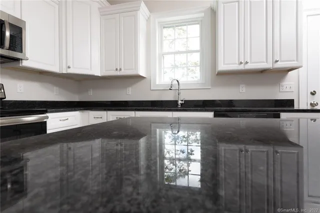 a kitchen with granite countertop white cabinets and a sink