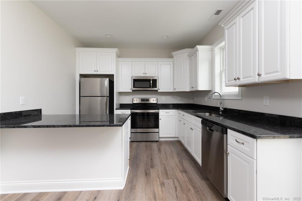 29 Covey Road, Unit 13 Burlington, CT 06013 - Photo 7 of 34 a kitchen with granite countertop a refrigerator sink and white cabinets