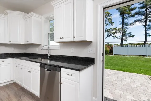 a kitchen with granite countertop a sink and white cabinets