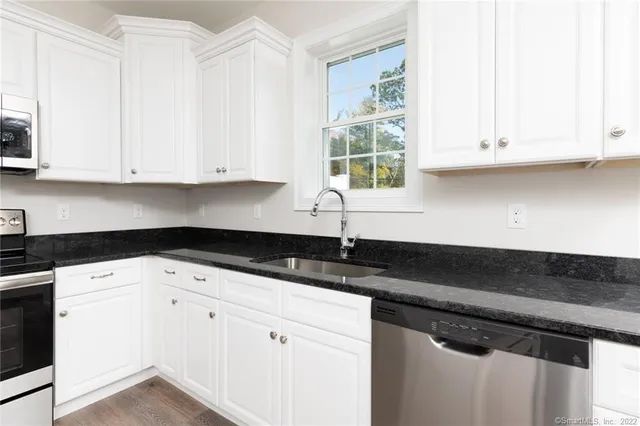 a kitchen with granite countertop white cabinets and a sink