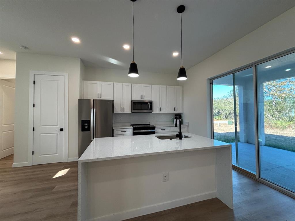 15215 Southwest 43rd Court Ocala, FL 34473 - Photo 10 of 29 a large kitchen with stainless steel appliances granite countertop a refrigerator a oven a sink with a countertop and wooden floor