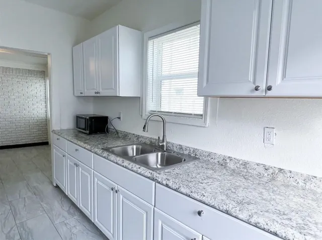 a kitchen with granite countertop a sink a window and cabinets