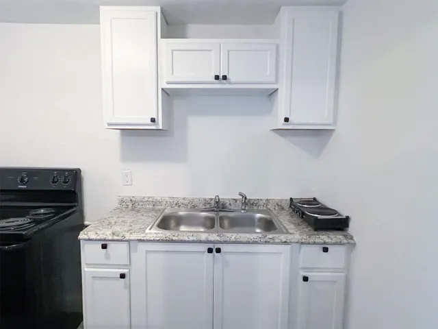 a kitchen with granite countertop a sink cabinets and stainless steel appliances