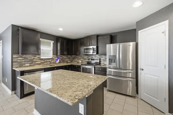 a kitchen with stainless steel appliances granite countertop a refrigerator stove microwave and sink