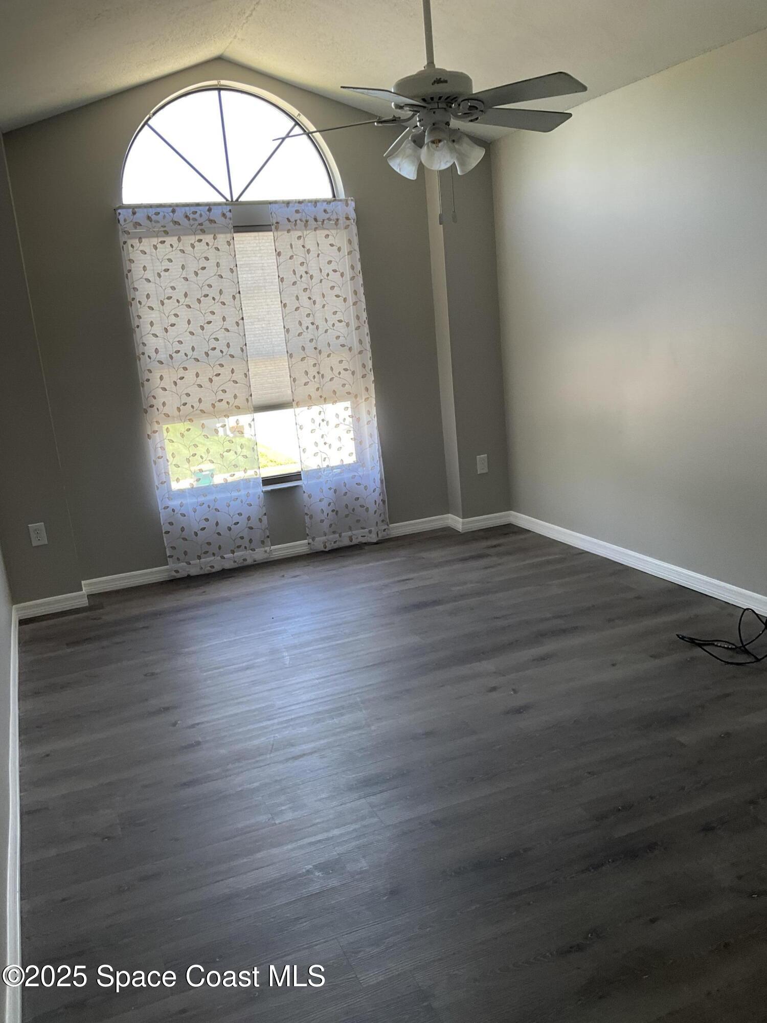 1668 Clover Circle Melbourne, FL 32935 - Photo 13 of 16 an empty room with wooden floor chandelier and windows