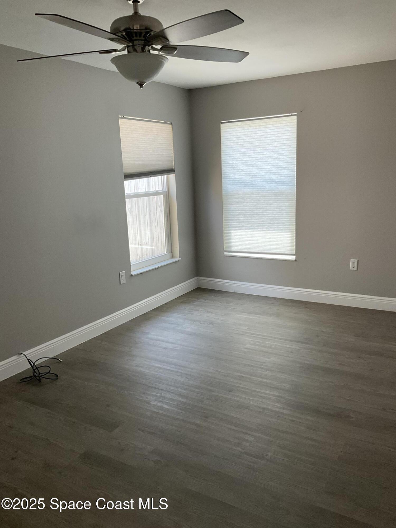 1668 Clover Circle Melbourne, FL 32935 - Photo 14 of 16 an empty room with wooden floor chandelier fan and windows