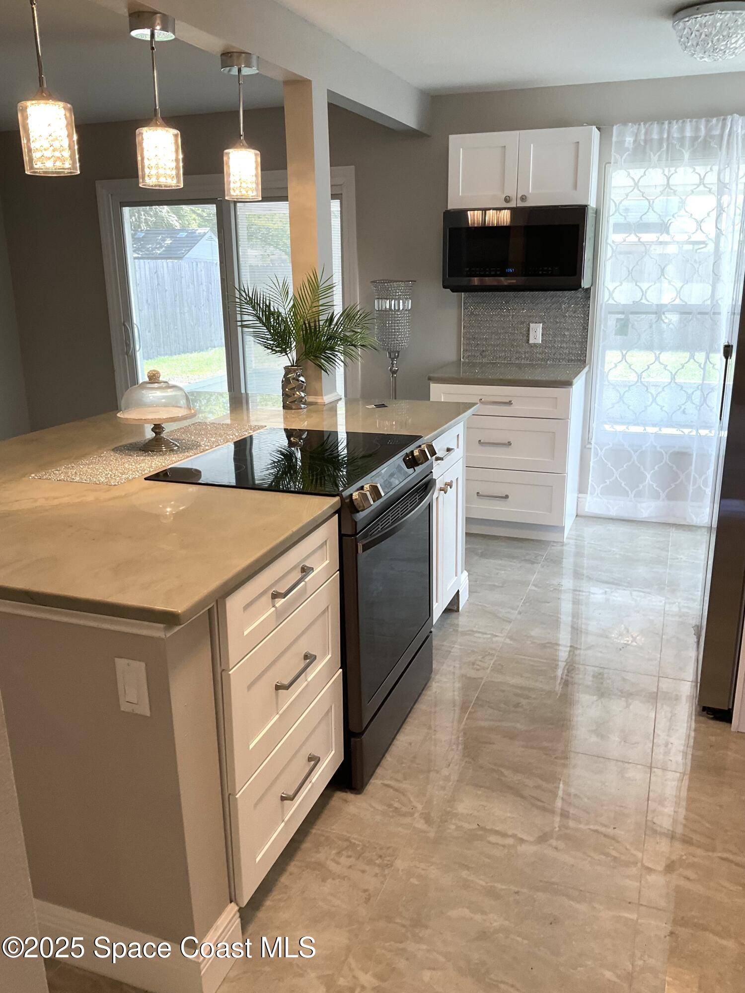 1668 Clover Circle Melbourne, FL 32935 - Photo 3 of 16 a kitchen with stainless steel appliances kitchen island granite countertop a stove a sink and a microwave