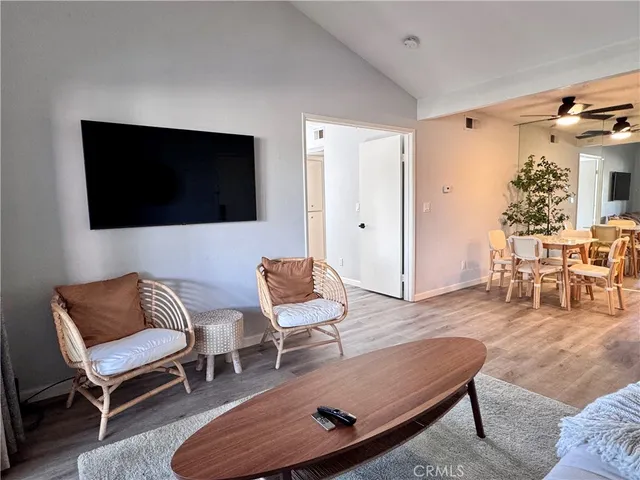 a kitchen with stainless steel appliances granite countertop a stove a refrigerator a kitchen island a dining table and chairs with wooden floor