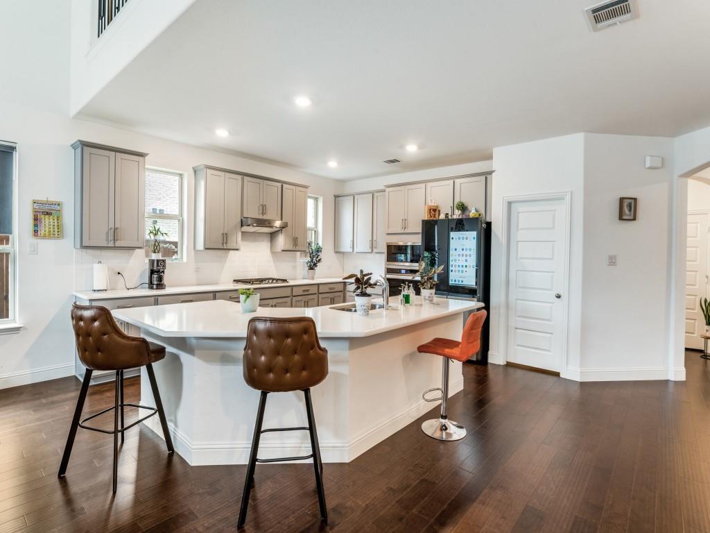 3120 Stonelake Ridge Lewisville, TX 75010 - Photo 4 of 17 a kitchen with stainless steel appliances granite countertop a stove a sink a refrigerator and white cabinets with wooden floor