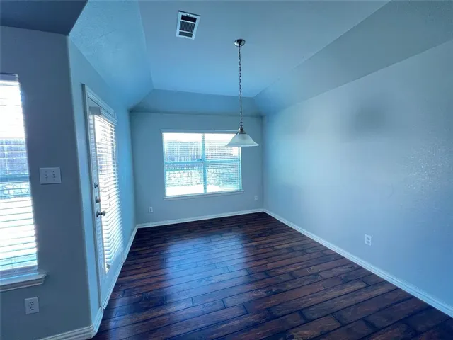 a view of an empty room with a kitchen and wooden floor