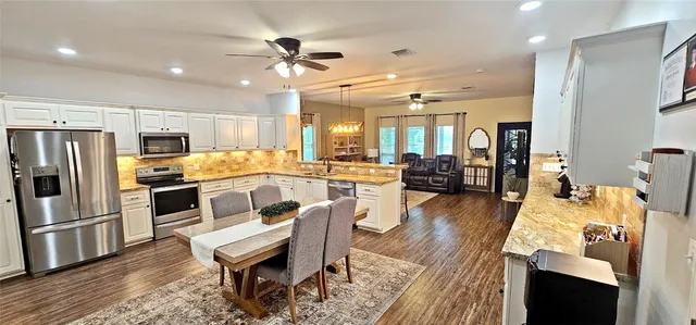 a large kitchen with a table chairs refrigerator and microwave