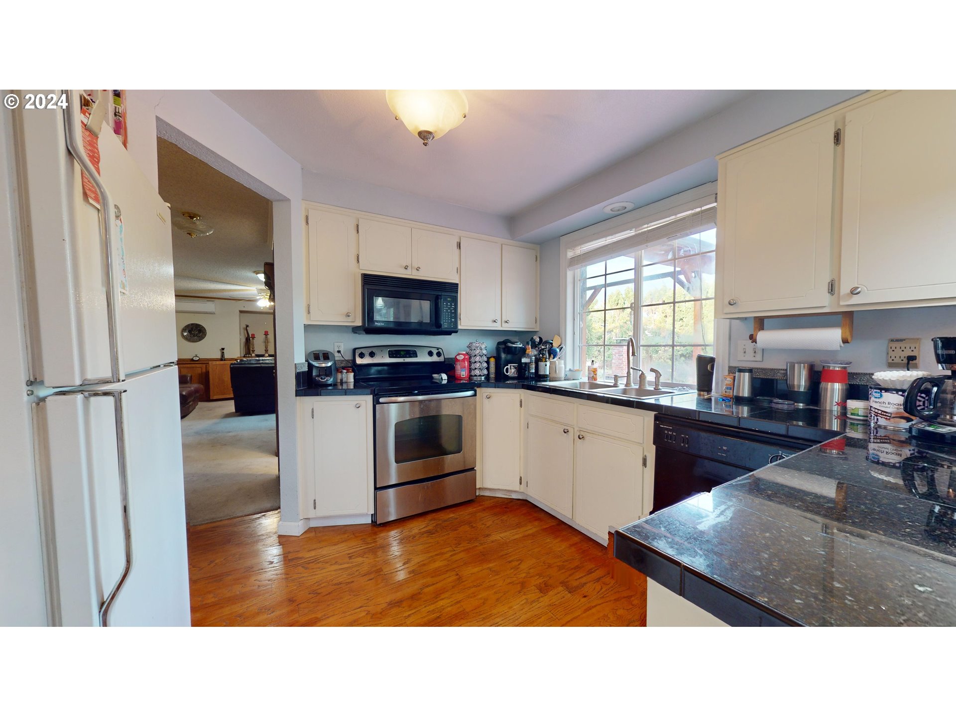 631 Rayner Avenue Springfield, OR 97477 - Photo 10 of 40 a kitchen with stainless steel appliances kitchen island granite countertop a refrigerator oven a sink dishwasher and white cabinets with wooden floor