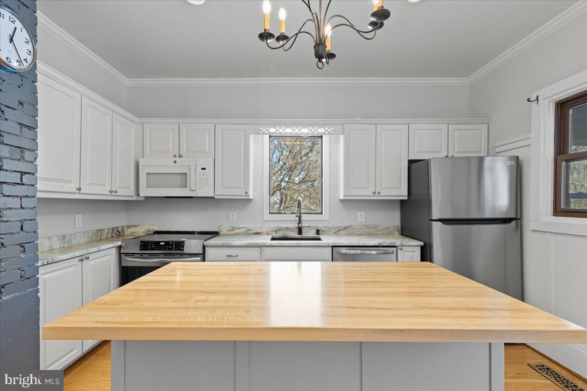 23320 Watson Road Leesburg, VA 20175 - Photo 7 of 51 a kitchen with kitchen island a refrigerator a stove a sink and white cabinets