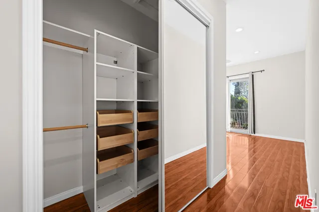 a view of walk in closet with wooden floor
